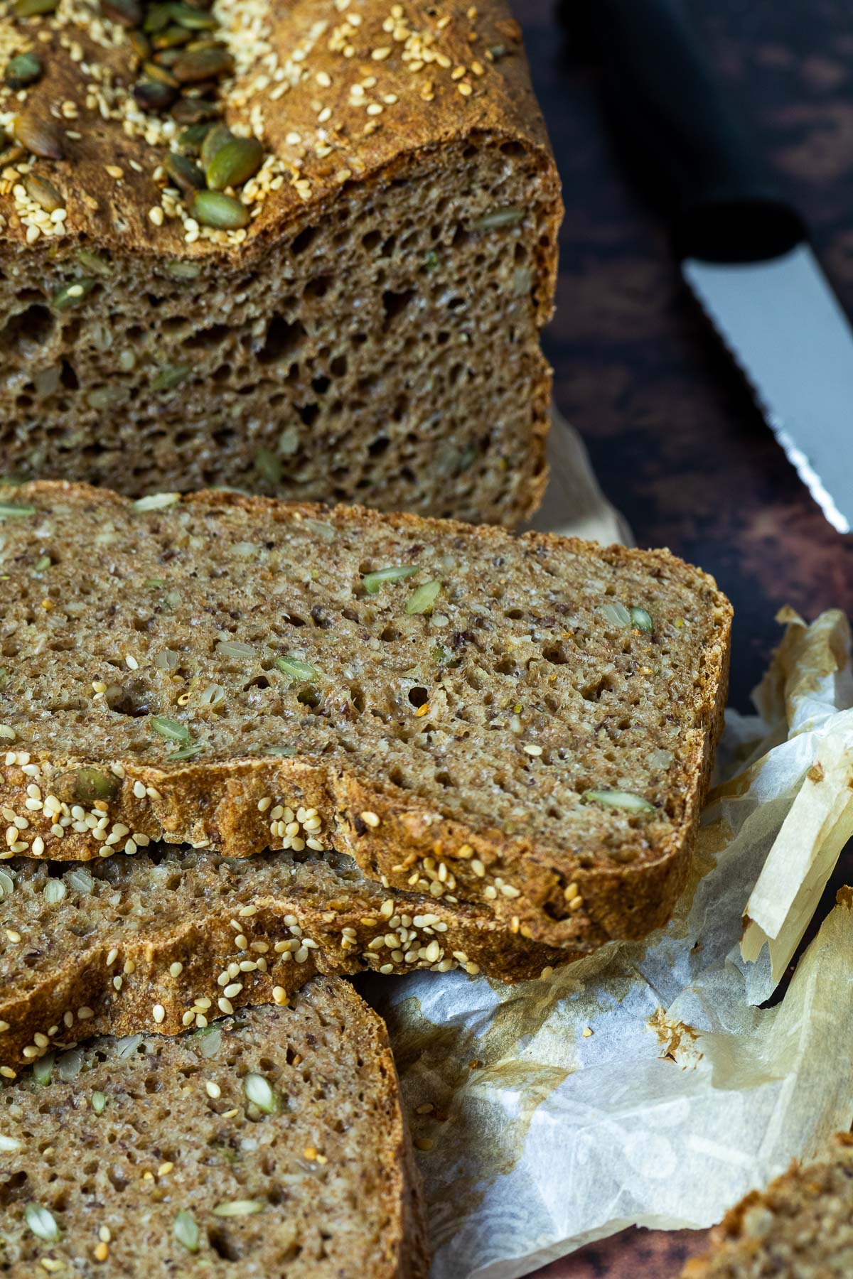 Spelt bread on parchment paper with some slices in front