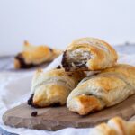 In focus a half chocolate croissants with flaky layers .