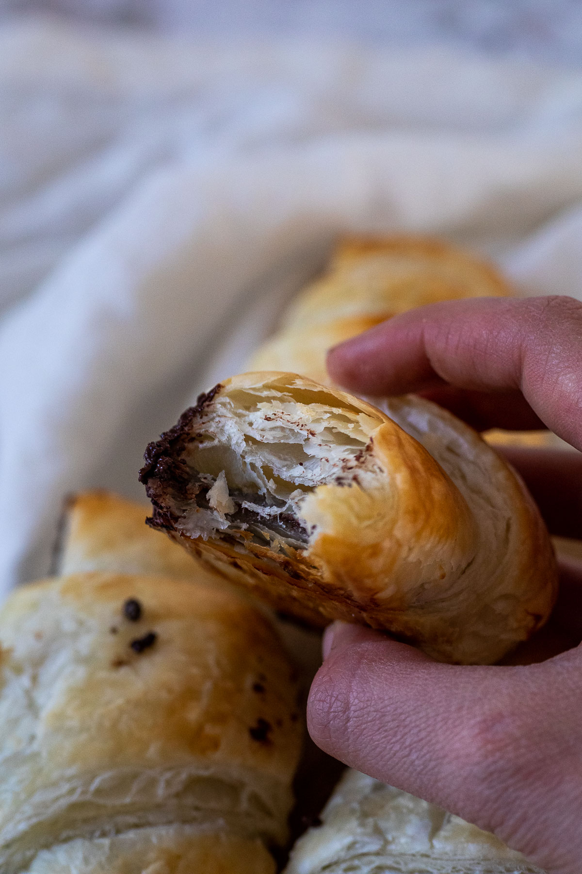 Holding a vegan chocolate croissants with flaky layers