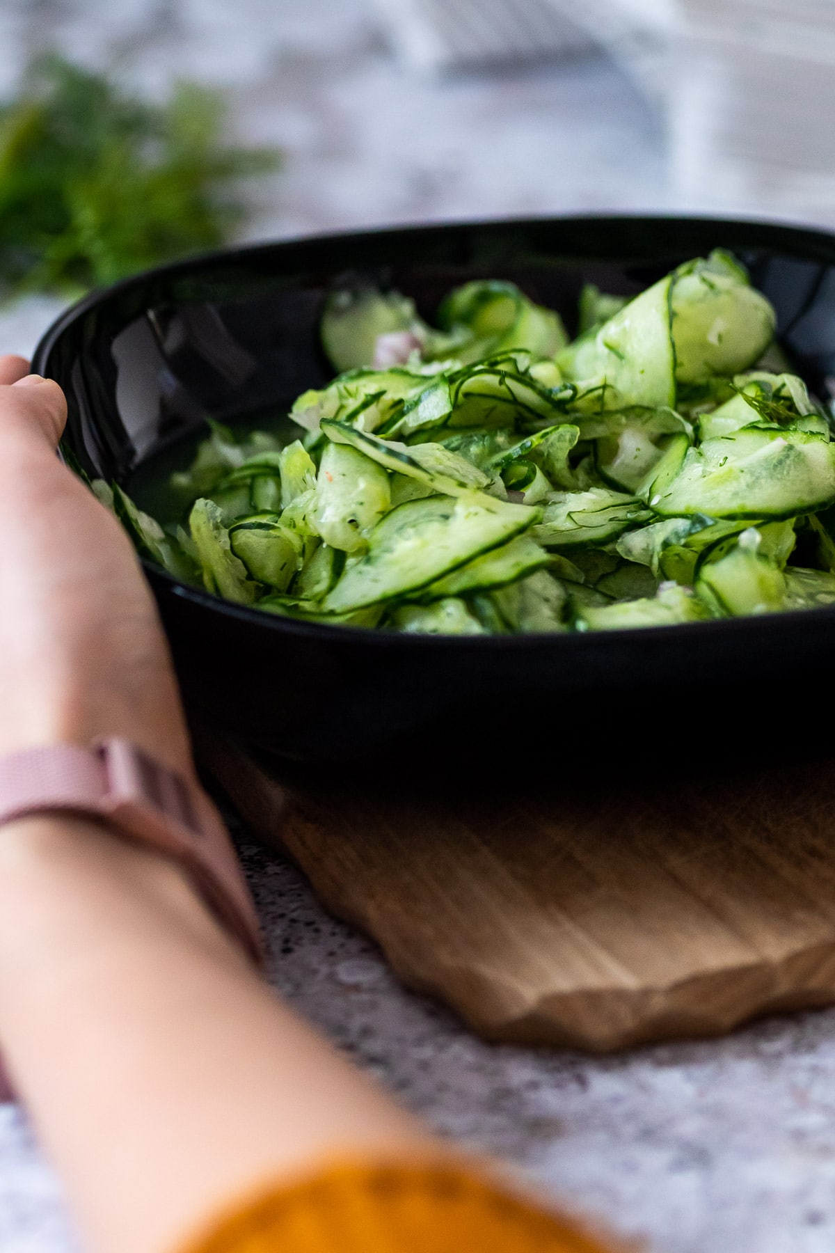 Holding a black bowl with cucumber salad