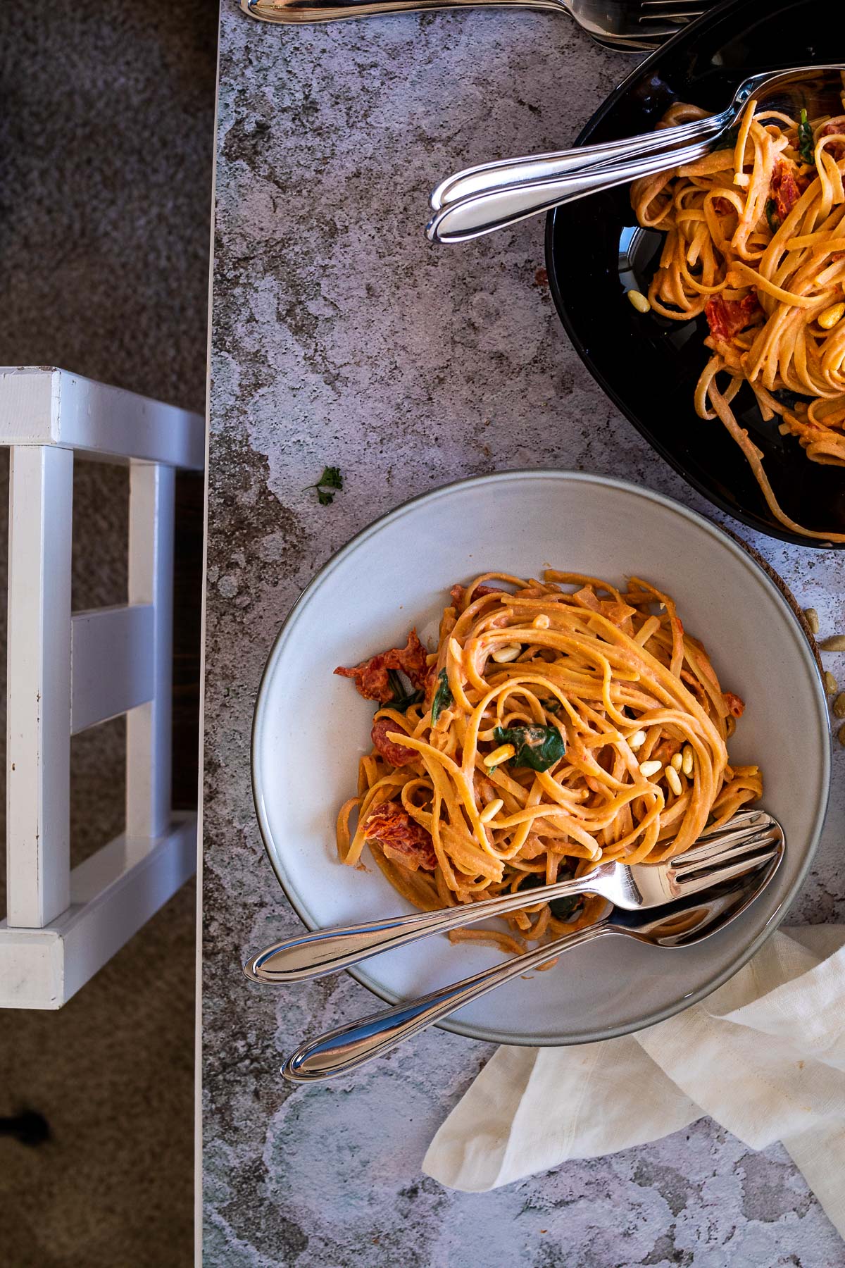 Two tomato alfredo spaghetti bowl with a chair in front