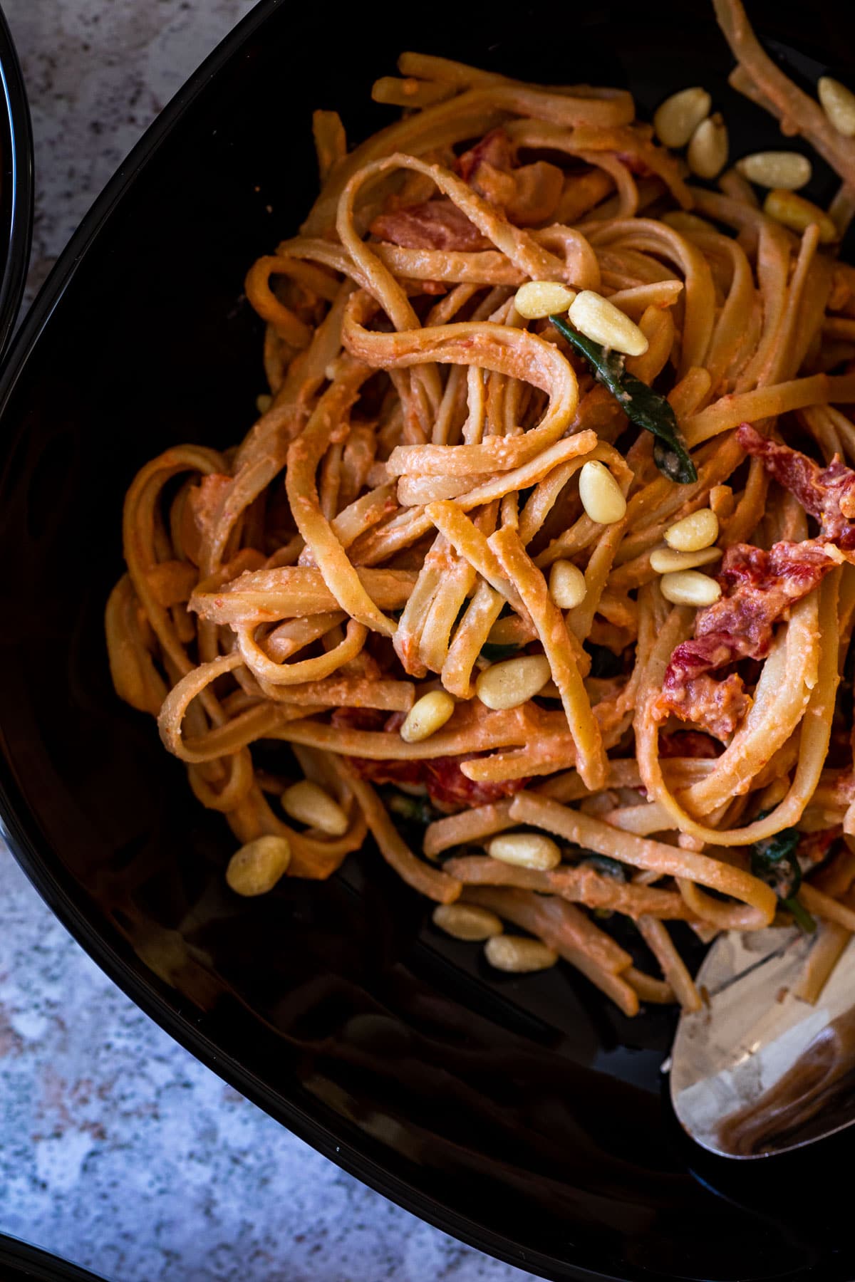 Close up of the tomato alfredo sauce with spaghetti and topped with pine nuts