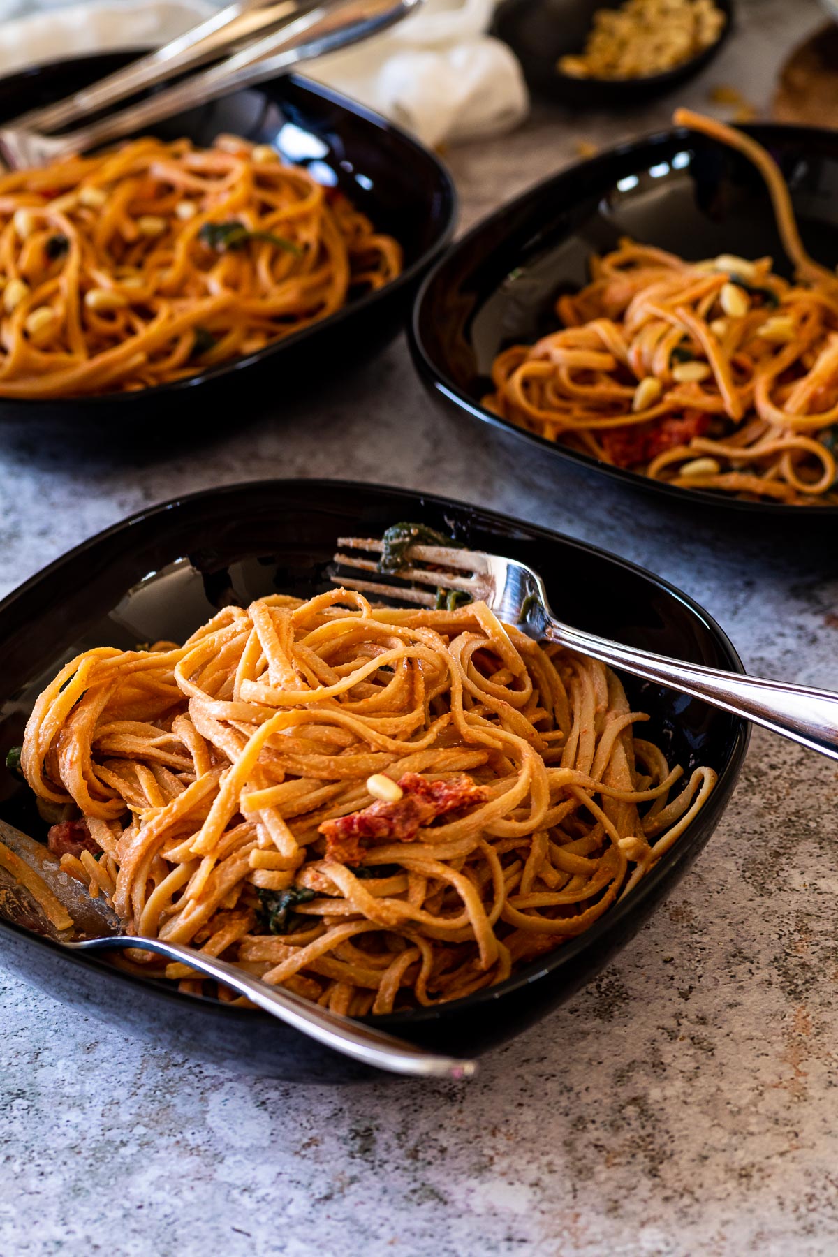 3 bowls with tomato alfredo spaghetti with sun dried tomatoes and spinach