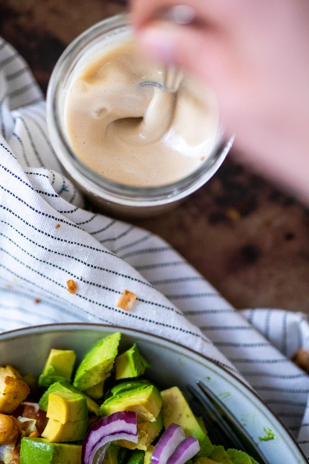 Stirring a jar full of tahini dressing.