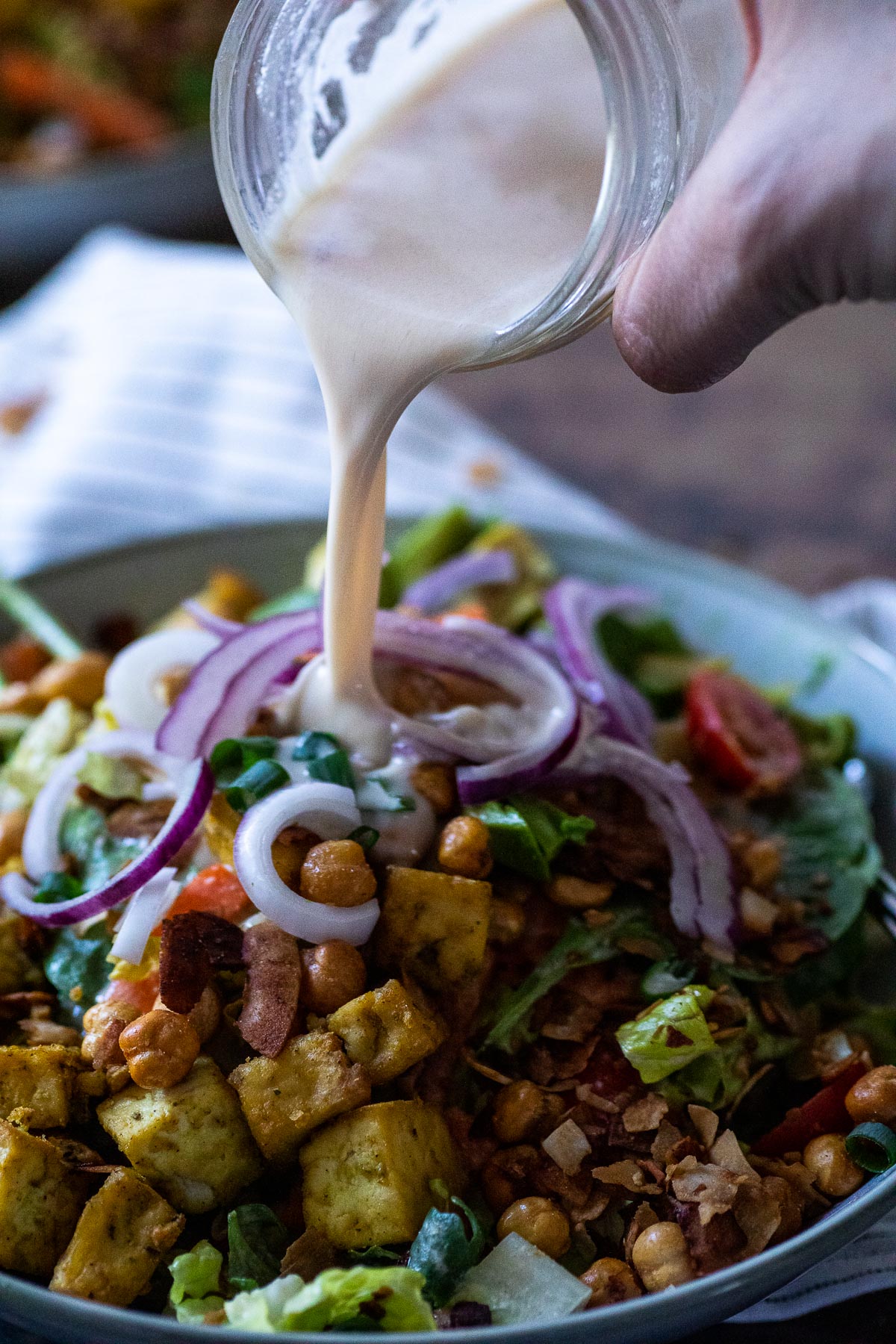 Pouring Some Tahini Dressing over a salad bowl.