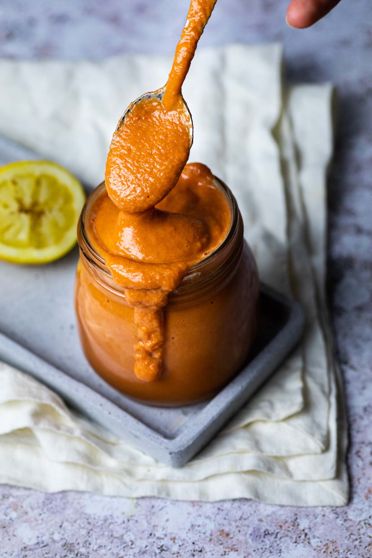 Holding a spoon with oil free vegan French Dressing over a jar french dressing