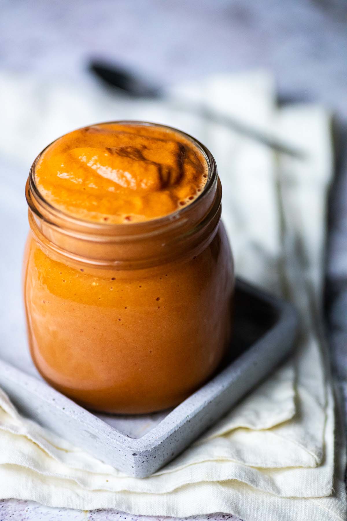 Glas gefüllt mit ölfreiem veganem French-Dressing auf einem Tuch und Brett