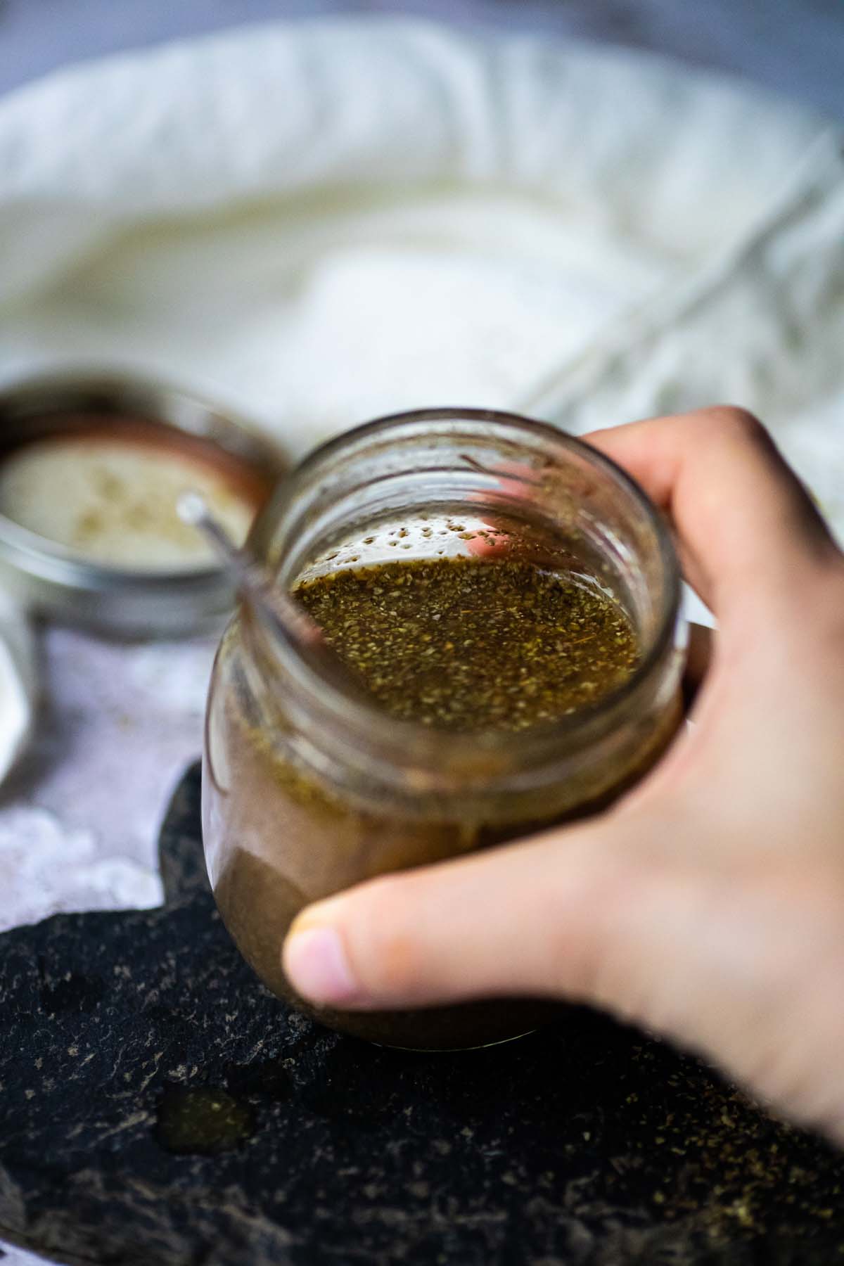 Halten eines Glas mit ölfreiem Balsamico-Dressing, um das Innere zu sehen