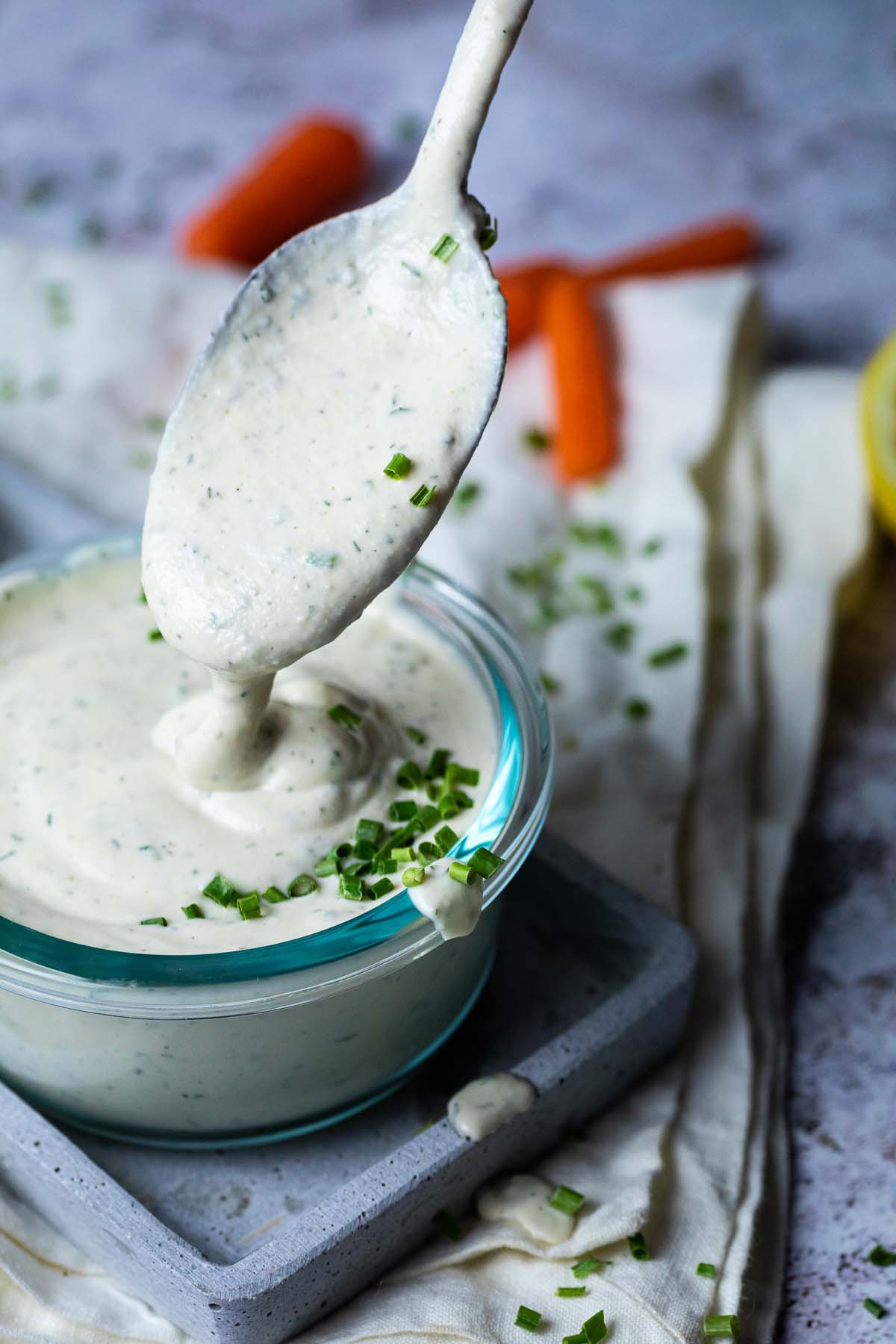 Einen Löffel mit veganer Ranch über einer Schüssel Ranch halten